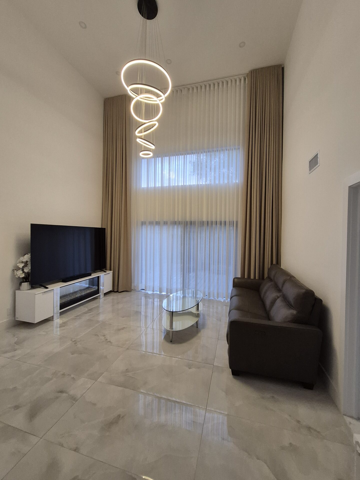 Two-story drapes and sheers in a double-height South Florida living room