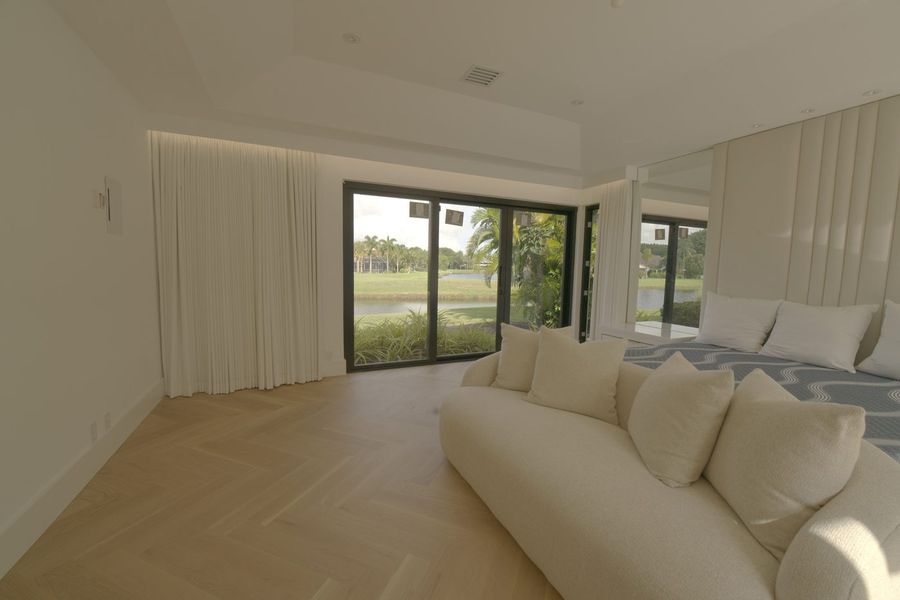 Ripplefold drapery drawn open in a Boca Raton master bedroom with the golf course visible through the glass doors