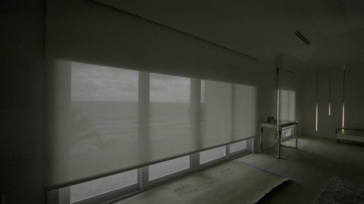 Luna White Lutron blackout shade rolling up off a wall of ocean glass, Hillsboro Beach