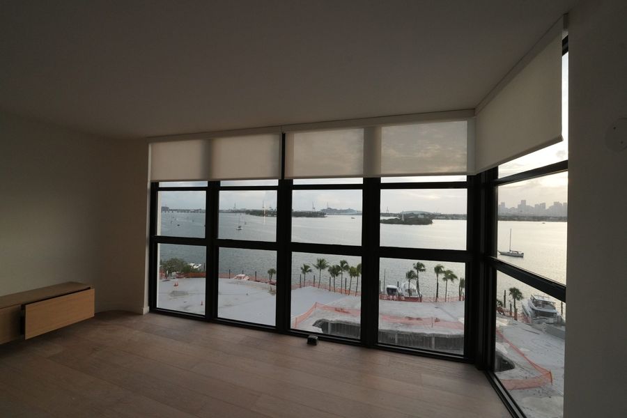 Roller shades half lowered on a glass wall facing the bay, South Beach, Miami Beach