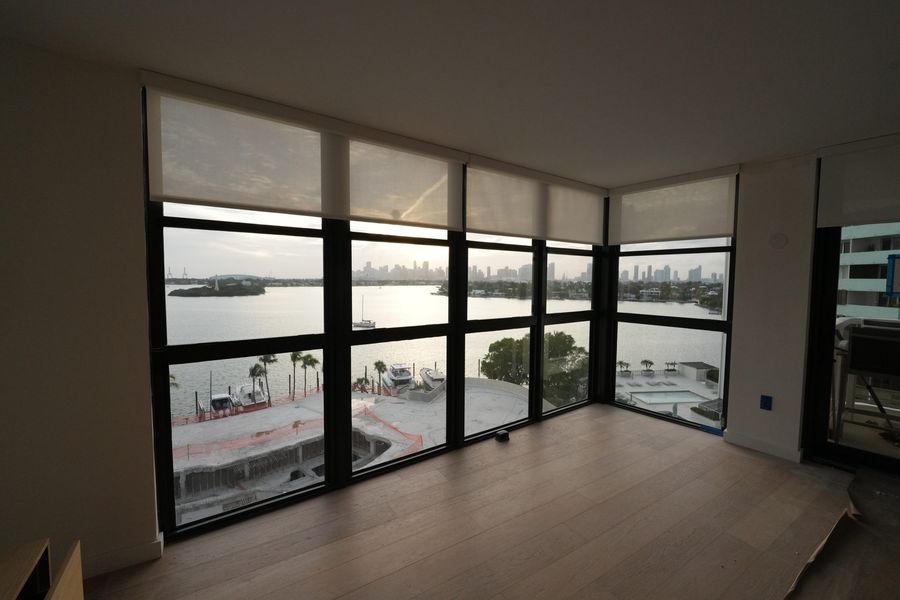 Light-filtering roller shades on floor-to-ceiling glass in a South Beach condo, Miami Beach