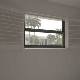 Guest house window with lacquered basswood shutter panels swung open and palm trees outside, Boca Raton