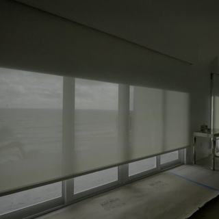 Luna White Lutron blackout shade rolling up off a wall of ocean glass, Hillsboro Beach