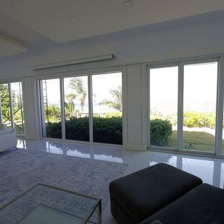 Motorized Lutron shades across the oceanfront living room glass of a Hillsboro Mile mansion
