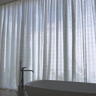 Primary bathroom with a freestanding tub against floor-to-ceiling sheer draperies, Miami Beach