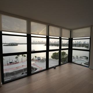 Light-filtering roller shades on floor-to-ceiling glass in a South Beach condo, Miami Beach