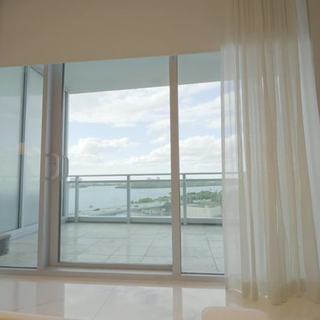 Bedroom sheer draperies at an open slider with the bay beyond, Sunny Isles Beach