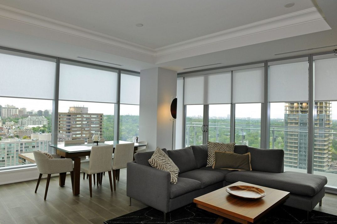 Condo living room with floor-to-ceiling glass and roller shades mounted at the ceiling across the full span