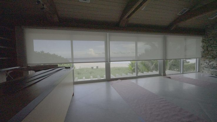 Five Somfy Sonesse 30 Zigbee roller shades lowering together across the great room sliders at Bay Drive, Pompano Beach