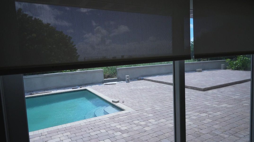 SheerWeave 4000 Eco solar screen lowering over the pool and sea grape view on a Somfy Sonesse 30 Zigbee motor