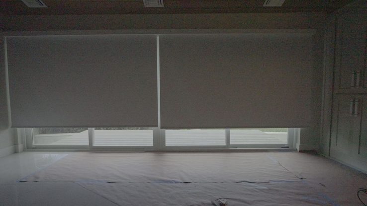 Primary suite bedroom with the SheerWeave 7200R Swan blackout shade lowered across the sliding glass