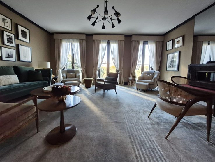 Living room with three French windows dressed in chenille drapery and striped sheers