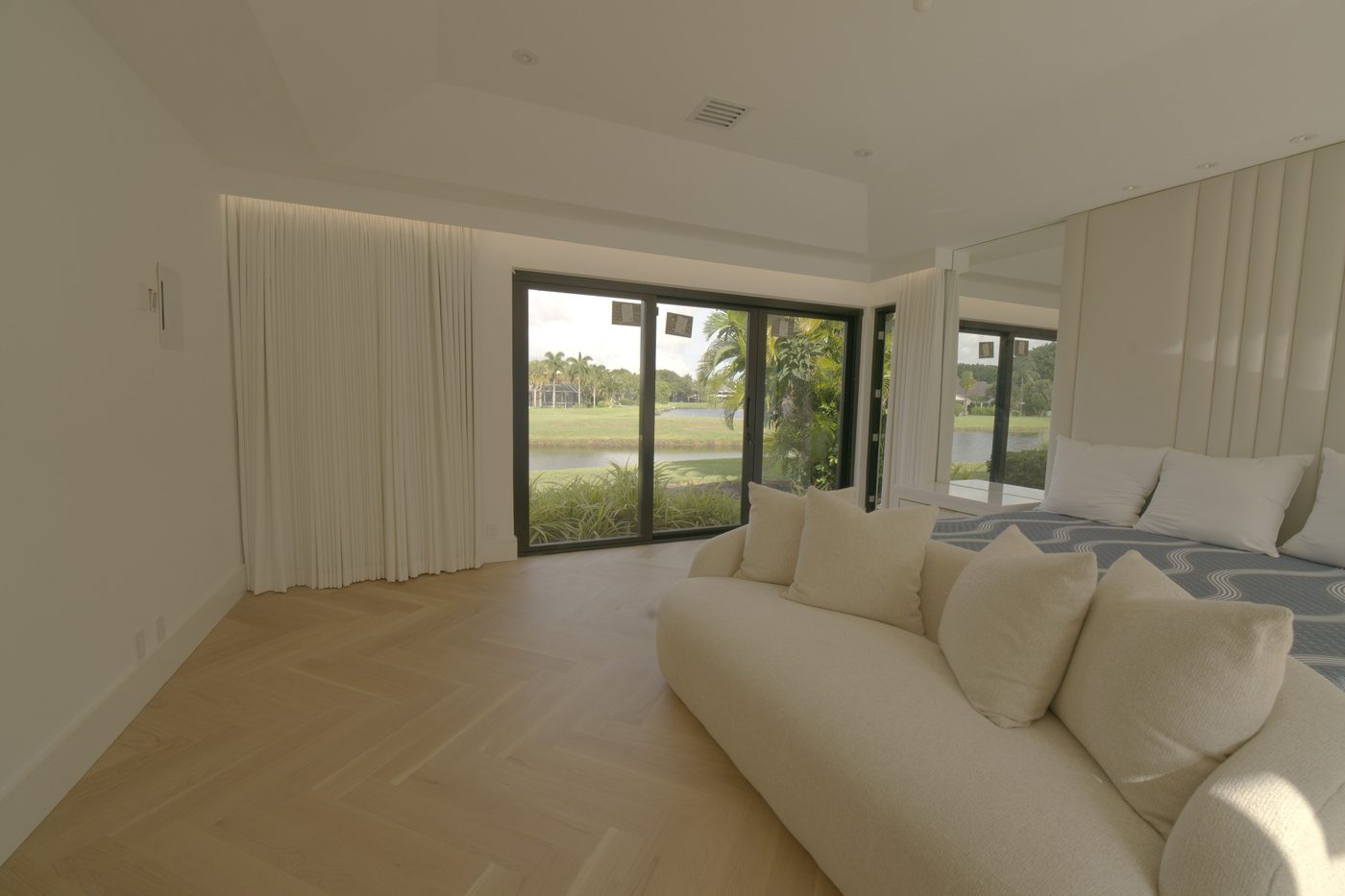Master bedroom with the ripplefold drapery stacked open and the golf course through the glass doors