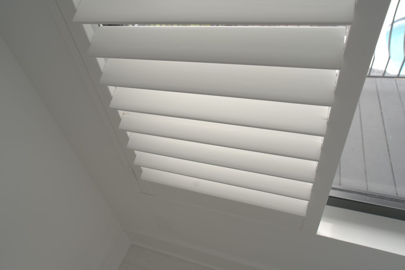 Close-up of lacquered basswood shutter louvers with no visible tilt rod on a high guest house window in Boca Raton