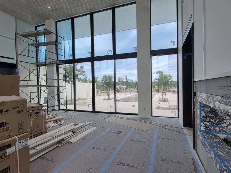 A wall of glass about twenty-four feet high with scaffolding and boxes on the floor during construction