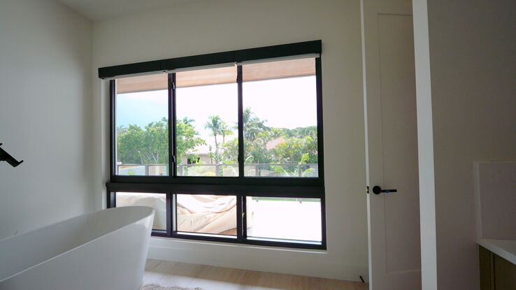 Master bathroom tub window with three Lutron Aura 3% Parchment roller shades raised