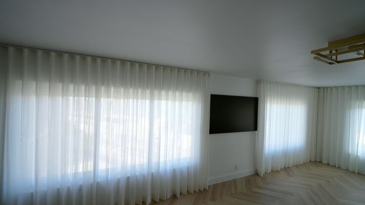 Living room with the Villa Nova Geneva cotton-linen sheers drawn across the ocean wall on a recessed track
