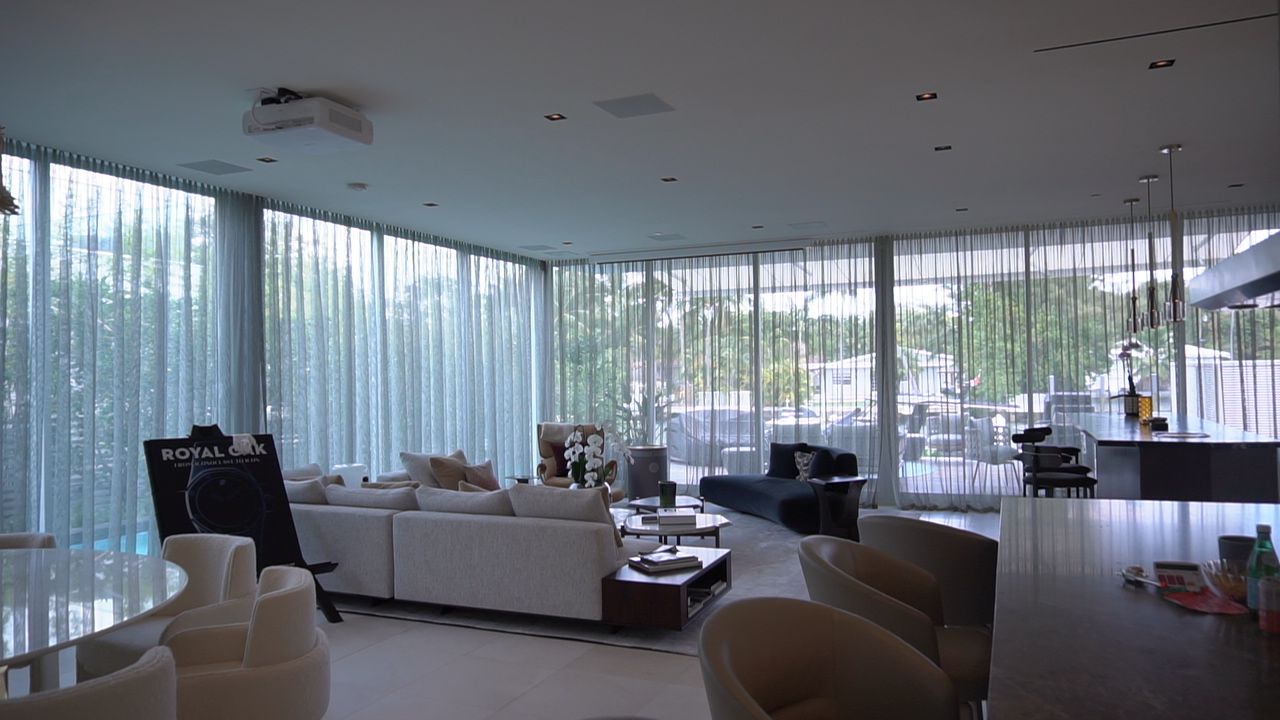 Social areas with ripplefold sheers drawn across a full wall of glass over the water